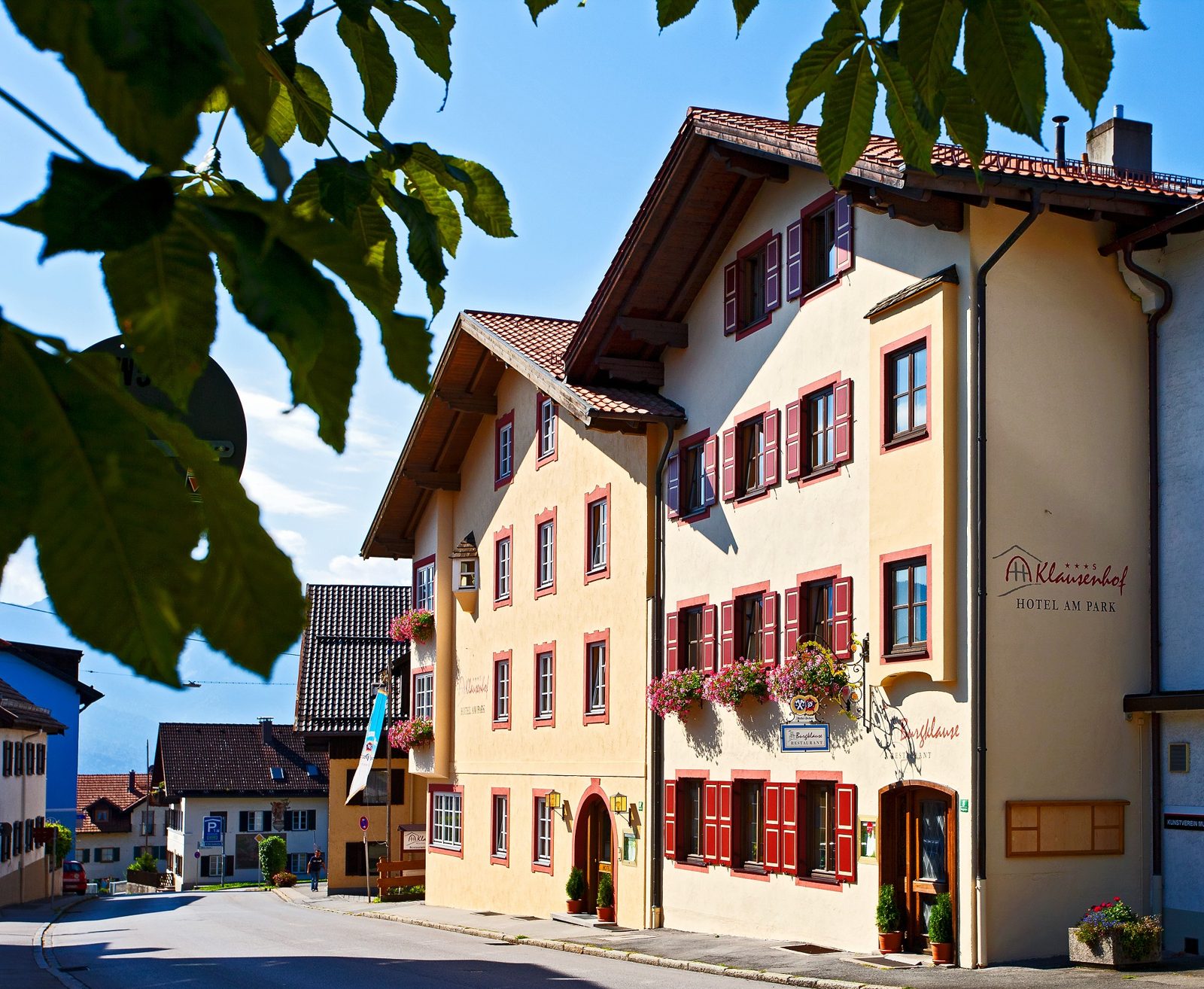 Blick durch eine sommerliche Murnauer Gasse mit bayerischen Fassaden und Bergen im Hintergrund