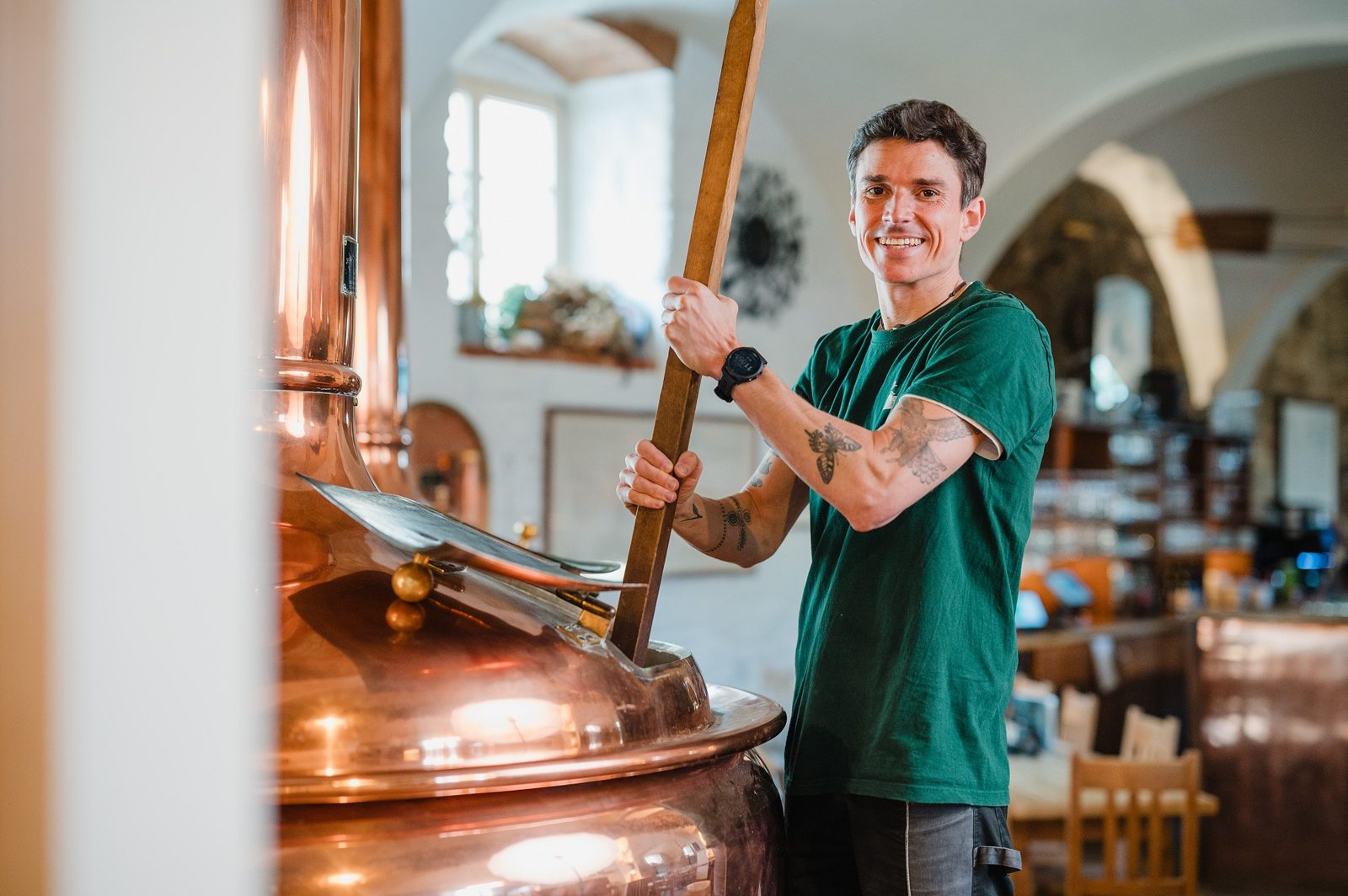 Braumeister rührt mit einem Holzscheit im kupfernen Sudkessel der Hausbrauerei