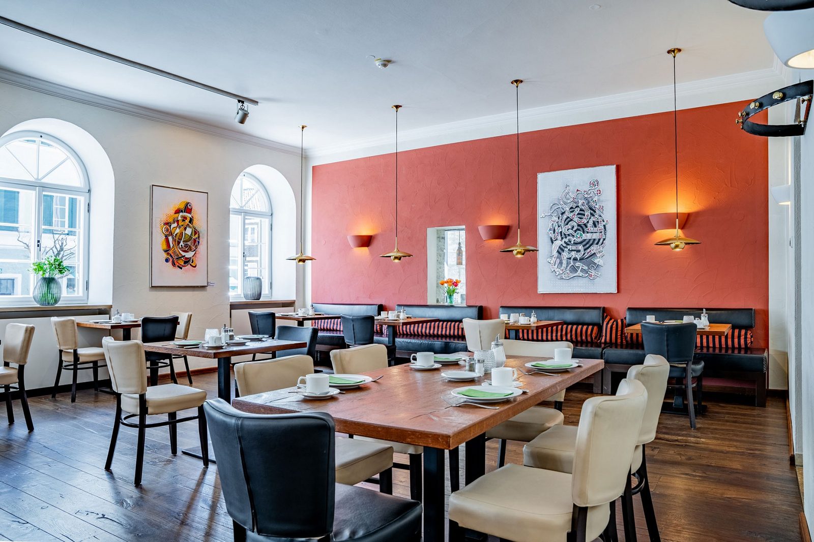 Heller, moderner Frühstücksraum des 4-Sterne-Hotels mit warmer Wandfarbe und Kunst